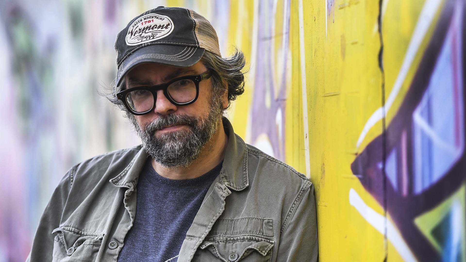 Portrait of Argentine artist Liniers beside a colorful mural